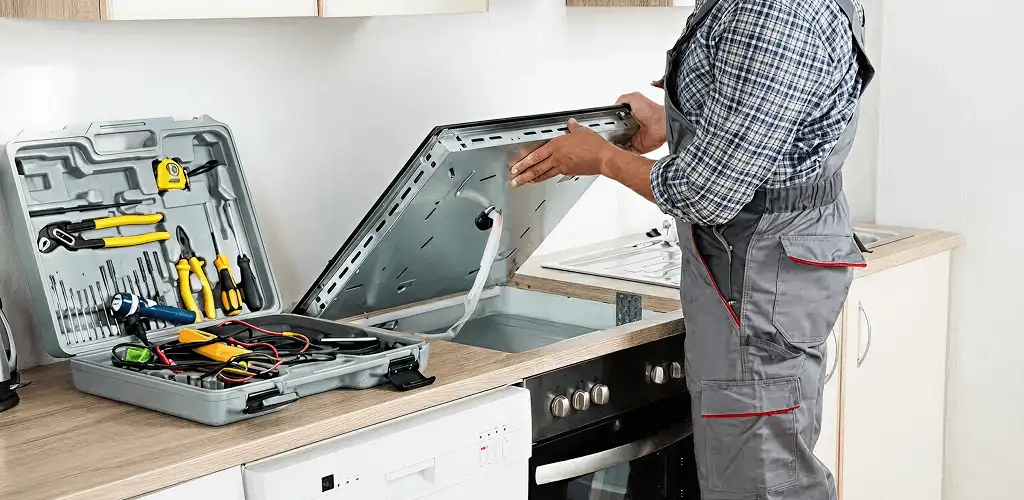 Handyman repairing a cooktop and checking wiring connections in Lakewood, CO