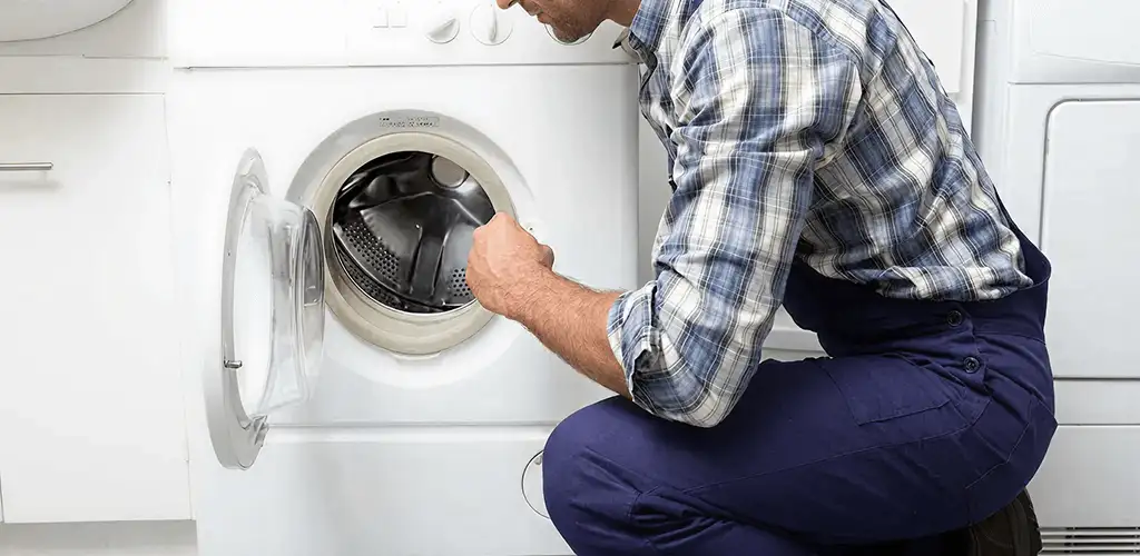 Handyman inspecting a dryer drum and internal parts for repair in Lakewood, CO