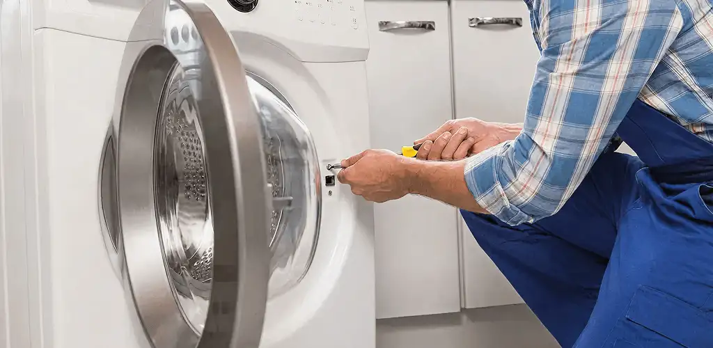 Handyman repairing a clothes dryer and checking electrical connections in Lakewood, CO