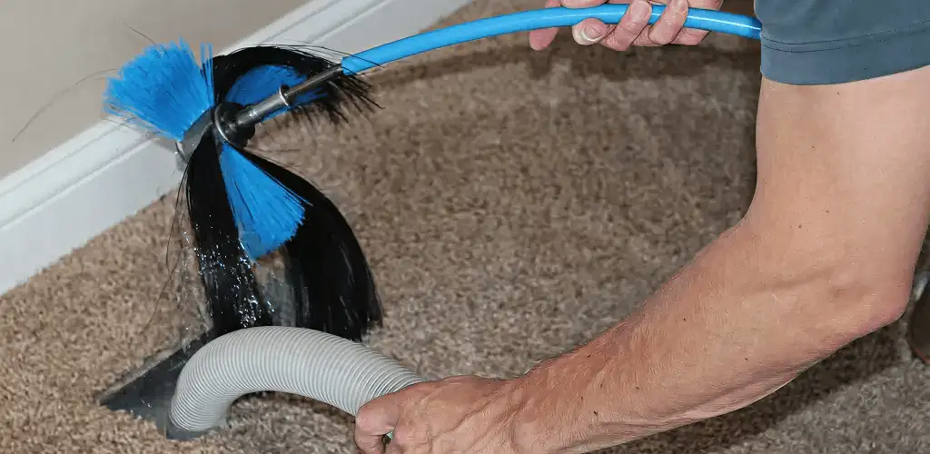 Dryer vent cleaning technician brushing lint from a vent line in Lakewood, CO
