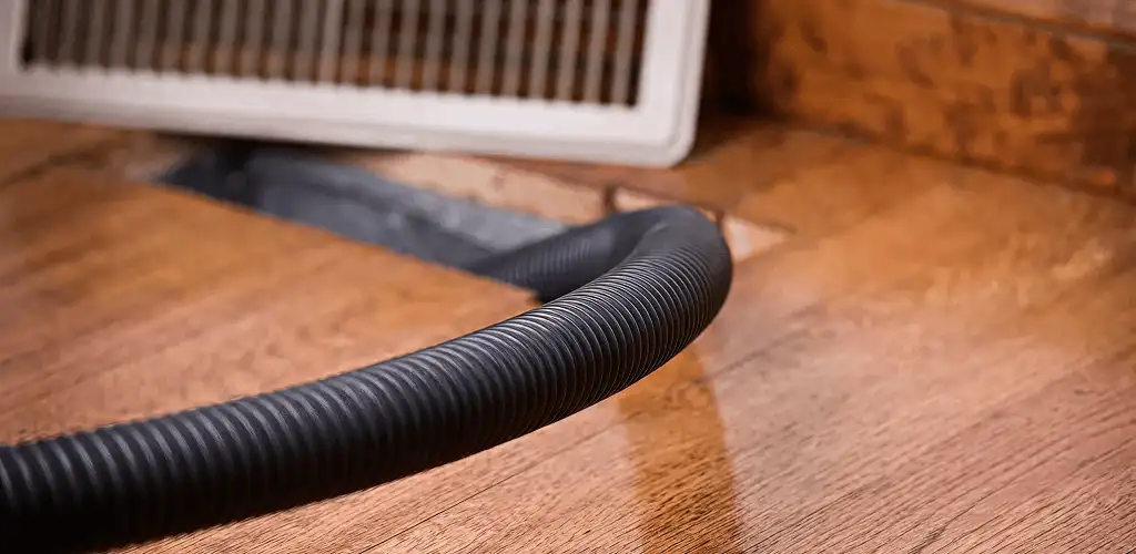 Air duct cleaning hose inserted into a floor vent for ductwork cleaning in Lakewood, CO
