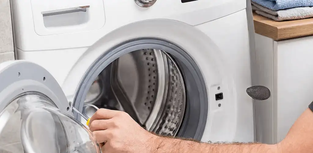 Handyman repairing a front-load washing machine and inspecting the drum in Lakewood, CO