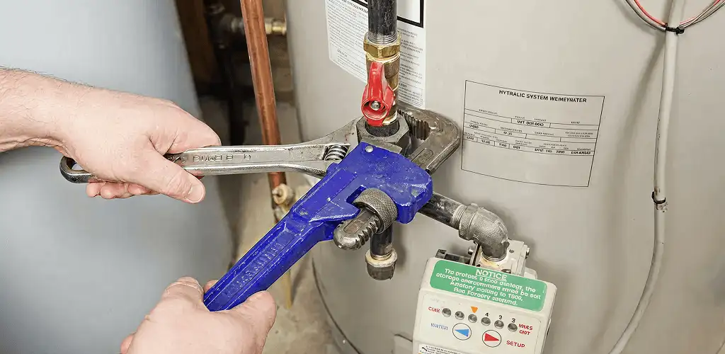 Water heater repair technician tightening the shutoff valve and supply line in Lakewood, CO